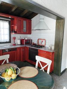 a kitchen with red cabinets and a table with a bowl of fruit at Ktima Zotos luxury exotic cottage in Agria