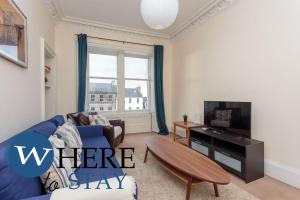 a living room with a blue couch and a tv at Delightful 2 bedroom apartment in Leith in Edinburgh