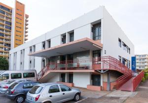 biały budynek z samochodami zaparkowanymi na parkingu w obiekcie Bittar Inn w mieście Brasília