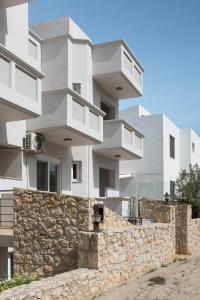 a white apartment building with a stone wall at Horizon Heaven apartment in Koumpeli
