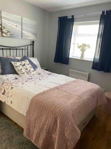 1 dormitorio con 1 cama con cortinas azules y ventana en Turnstone en Seaton
