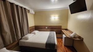 a small room with a bed and a phone at Aurora Hotel in Ribeirão Preto