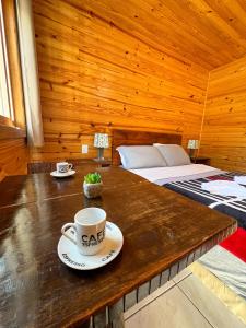 a cup of coffee on a wooden table in a room at Pousada Recanto da Gruta in Urubici