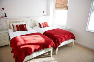 a bedroom with two beds with red and white blankets at Needles House in Milford on Sea