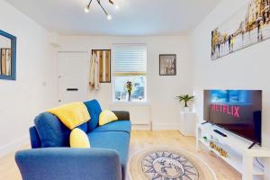 a living room with a blue couch and a tv at Charming Victorian Terrace House Quick Walk to Station in Kent