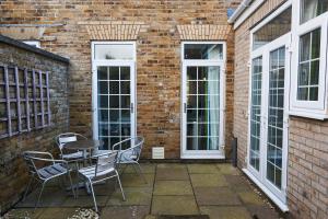 a patio with a table and chairs in front of a brick wall at Needles House in Milford on Sea