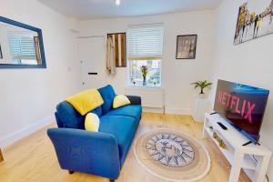 a living room with a blue couch and a tv at Charming Victorian Terrace House Quick Walk to Station in Kent