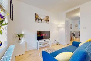 sala de estar con sofá azul y TV en Charming Victorian Terrace House Quick Walk to Station en Kent