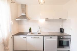 a kitchen with white cabinets and a sink at Le Douillet-T2-55m2-10min Disney in Bussy-Saint-Georges +13 photos