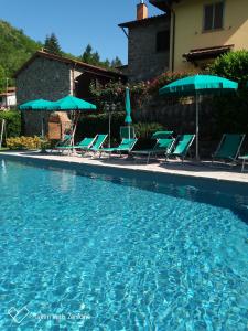 una piscina con sillas y sombrillas azules en Agriturismo Ristoro del Cavaliere, en Piazza al Serchio