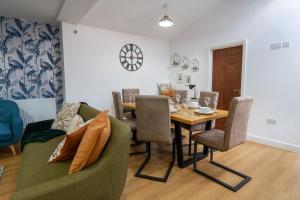 ein Esszimmer mit einem Tisch und einem grünen Sofa in der Unterkunft Heartland House, 7 Spacious Bedrooms Sleeps 4 plus, near NEC, JLR,BHX in Birmingham