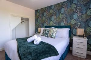 ein Schlafzimmer mit einem Bett mit einer grün gemusterten Wand in der Unterkunft Heartland House, 7 Spacious Bedrooms Sleeps 4 plus, near NEC, JLR,BHX in Birmingham