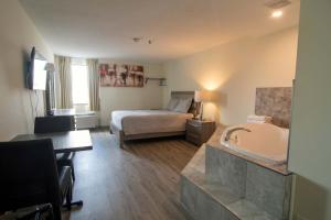um quarto de hotel com uma cama e uma banheira em Diplomat Inn em Cataratas do Niágara
