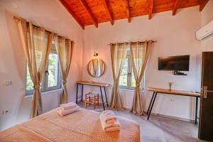 a bedroom with a bed and a tv and windows at Haroto Home Residence in Plokamianá