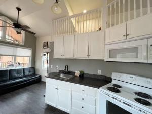 a kitchen with white cabinets and a white stove top oven at Alder Tiny Home in Woodland Park