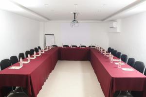 a long table in a room with red tables and chairs at Hotel Two Select in Culiacán