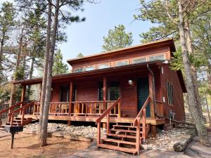 a log cabin in the woods with a large deck at Cabin Suite in Woodland Park