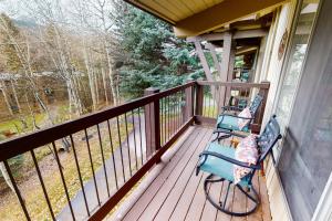 two chairs sitting on a porch with a view of the woods at Peaceful Woodbridge Hideaway in Snowmass Village