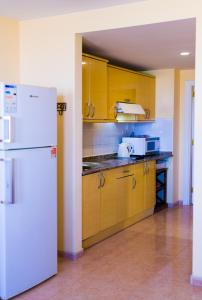 コラレホにあるOasis vistamarのキッチン(黄色のキャビネット、白い冷蔵庫付)