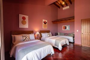 HOLT Balcones Guesthouse - Two Double Beds Room في سان ميغيل دي الليندي: سريرين في غرفة بجدران وردية