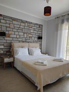 um quarto com uma cama grande e uma parede de tijolos em Iris Villas Complex em Lefkada