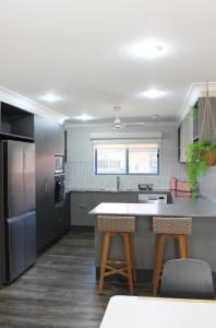 cocina con encimera y 2 taburetes en Yamba Twin Pines Motel, en Yamba