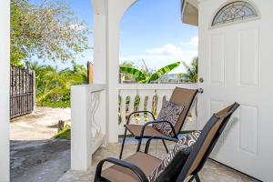 a pair of chairs on a porch with the door open at Palm Leaf Cottage in Montego Bay