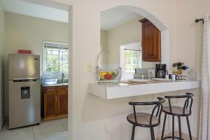 a kitchen with a refrigerator and two bar stools at Palm Leaf Cottage in Montego Bay