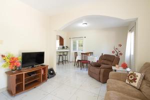 a living room with a couch and a tv at Palm Leaf Cottage in Montego Bay