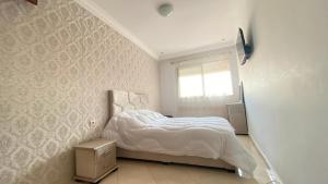 a white bedroom with a bed and a window at loubna 3 in Rabat