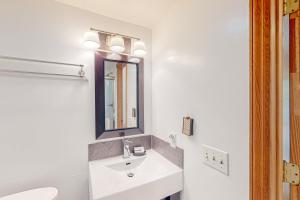 a white bathroom with a sink and a mirror at Wanderlust in Glen Arbor +17 photos