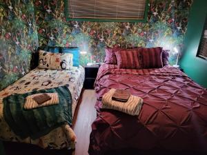 a bedroom with two beds and a wall with flowers at Hatea Treehouse in Whangarei