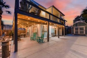 a house with a deck with green chairs at PCB Group Retreat with Deck, 1 Block to Beach! in Panama City Beach
