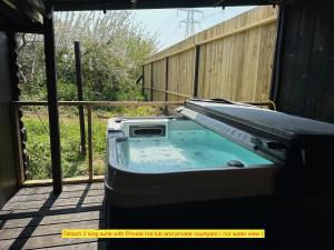 a hot tub on a porch with a fence at TheWaterfrontLodges in Coventry