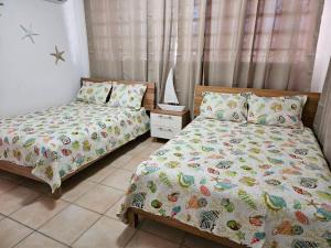 - une chambre avec 2 lits jumeaux et une table de nuit dans l'établissement Combate Whitehouse, Playa Combate, Cabo Rojo, à Cabo Rojo