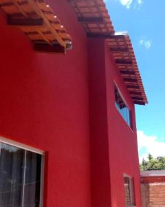 a red wall of a house with a window at Em Busca Hostel in Bonito