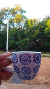 a person holding a blue and white coffee cup at Em Busca Hostel in Bonito