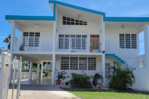 une maison blanche avec un toit bleu dans l'établissement Combate Whitehouse, Playa Combate, Cabo Rojo, à Cabo Rojo