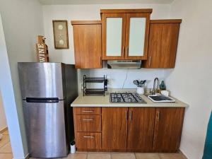 La cuisine est équipée d'armoires en bois et d'un réfrigérateur en acier inoxydable. dans l'établissement Combate Whitehouse, Playa Combate, Cabo Rojo, à Cabo Rojo