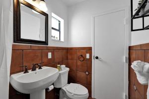 a bathroom with a sink and a toilet and a mirror at Waves On Walnut - Beach Access in Hollywood