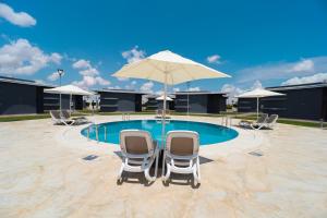 two chairs and an umbrella next to a pool at Rim Aquatique Hôtel & Nature in Fez