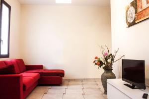a living room with a red couch and a vase with flowers at Appartamento Ghalà in Galatone