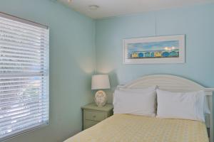 a white bedroom with a bed and a window at Longboard in Holmes Beach