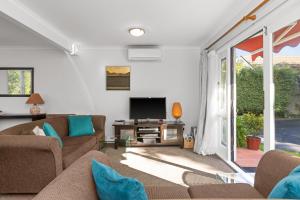 sala de estar con sofá y TV en Village Apartment Havelock North en Havelock North