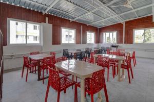 a dining room with red chairs and tables and windows at Global Stay Near Kengeri Bus Terminal Metro Station in Bangalore