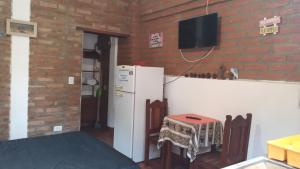 a kitchen with a white refrigerator and a tv on a brick wall at Alojamiento Los Amigos in Vaqueros