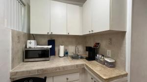 cocina con armarios blancos y microondas en Cozy Rooms, en Homestead
