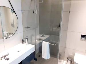 uma casa de banho com um chuveiro, um lavatório e um espelho. em 530 on the Parks em Joanesburgo