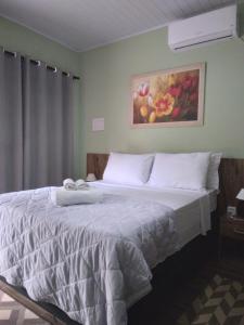 a bedroom with a white bed with a painting on the wall at Pousada da Serra Petar in Iporanga