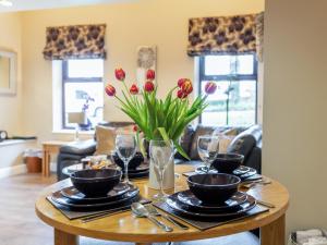 a table with plates and wine glasses and tulips at Ty Bach Twt in Dyffryn